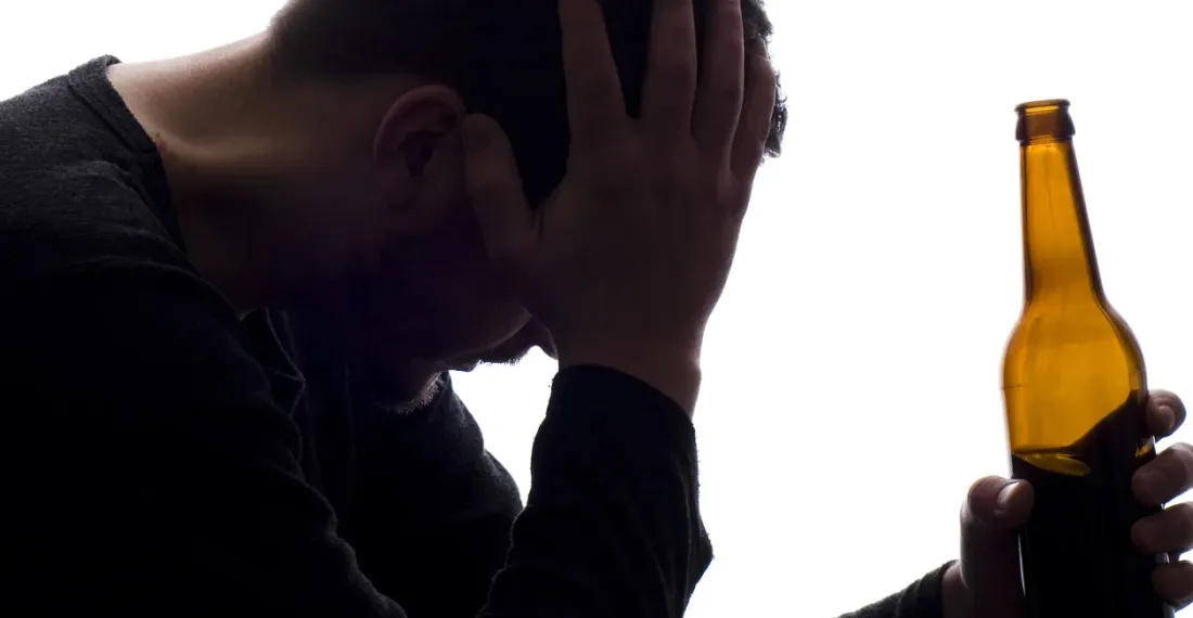 Мужчина держит бутылку с алкоголем