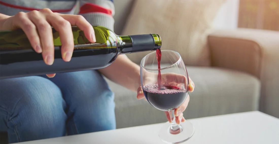 Женщина наливает вино в бокал