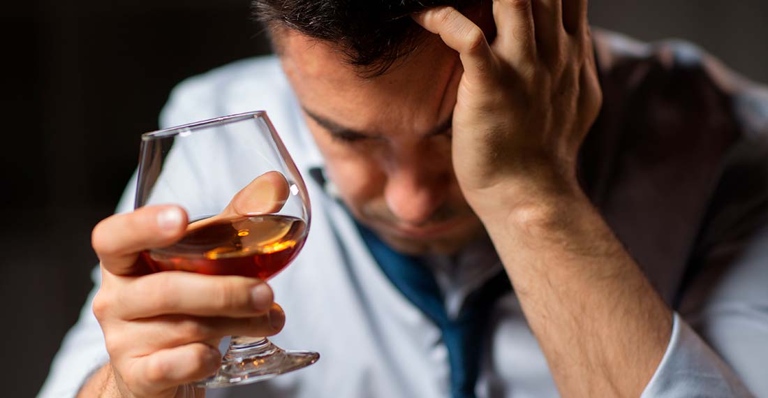 спящий мужчина со стаканом алкоголя в руке положил голову на руку