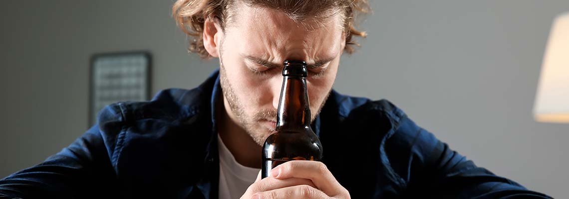 мужчина сидит, прислонив голову к бутылке